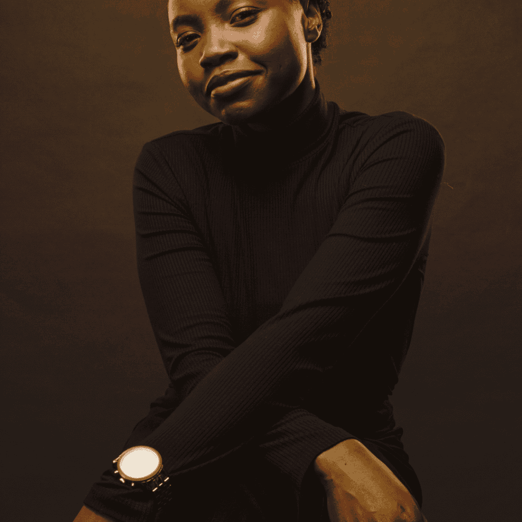 a beautiful dark skinned black woman wearing a black jumper, smiling.